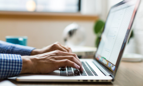 Individual typing on a laptop